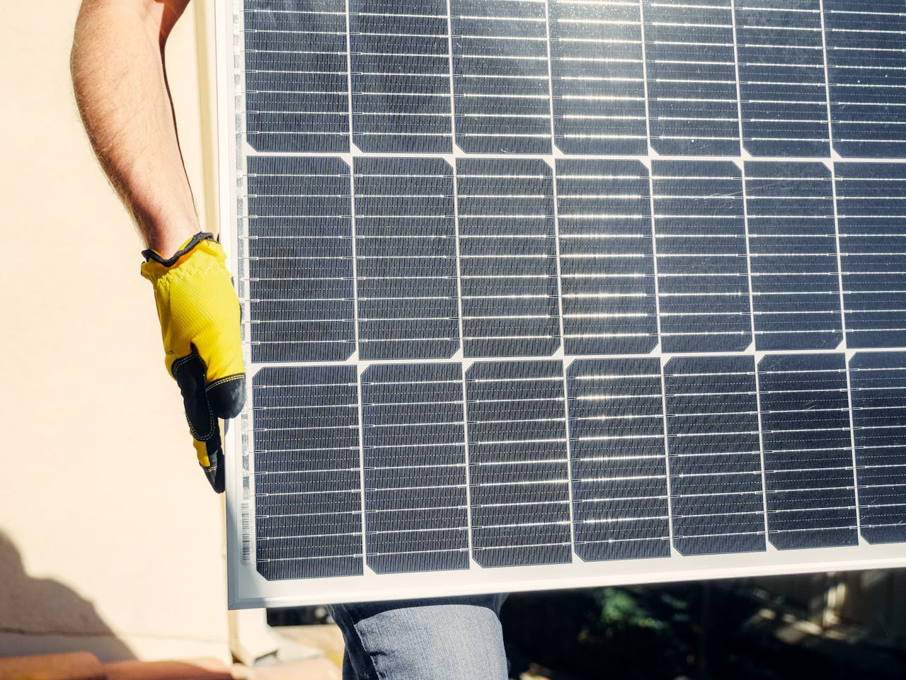 Close-up of a person installing a solar panel outdoors under bright sunlight.